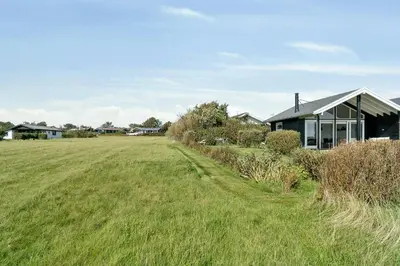 a field next to a house with a building at Cozy Home By Limfjord With Bathing Jetty in Snedsted