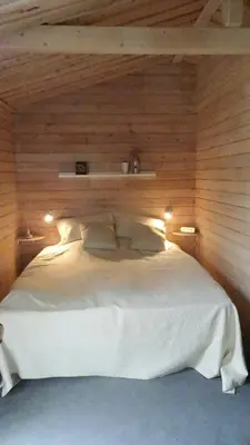 a bedroom with a white bed in a wooden wall at Charming Wooden Cottage Close To Handbjerg Beach in Vinderup