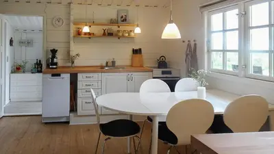 a kitchen with a white table and chairs at Charming Wooden Cottage Close To Handbjerg Beach in Vinderup