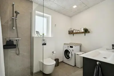 a bathroom with a washing machine and a sink at Modern Light House With Terrace Near The Fjord in Løgstrup