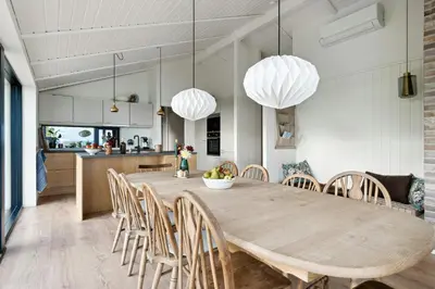 a kitchen and dining room with a wooden table and chairs at Cottage At Feggeklit With Limfjord Views in Nykøbing Mors