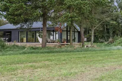 a house with a porch and trees and grass at Cottage At Feggeklit With Limfjord Views in Nykøbing Mors
