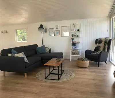 a living room with a couch and a table at Bright And Lovely Summerhouse In Løkken in Løkken