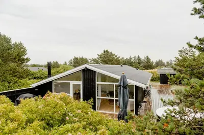 a small black house with a roof at Bright And Lovely Summerhouse In Løkken in Løkken