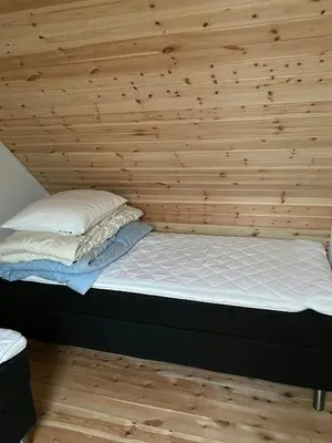 a bed in a room with a wooden wall at Renovated Farmhouse In Architectural Style in Lemvig