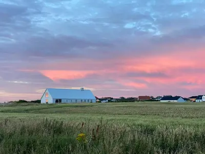 a white barn in the middle of a field at Renovated Farmhouse In Architectural Style in Lemvig