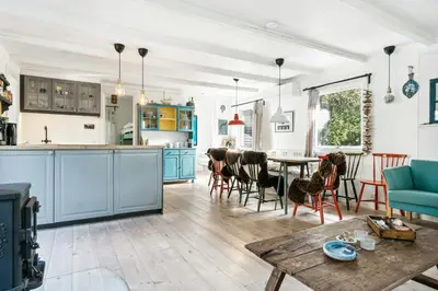 a kitchen and living room with blue cabinets and a table at Warm Colors And Beautiful Outdoors In Thy in Sønder Ydby