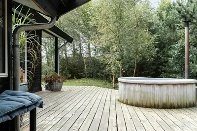a bath tub sitting on a wooden deck at Warm Colors And Beautiful Outdoors In Thy in Sønder Ydby