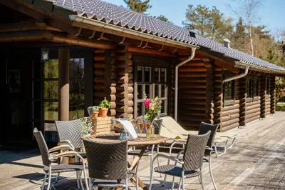 a wooden table and chairs outside of a log cabin at Authentic Log House Amid Evergreens In Vendsyssel in Fjerritslev