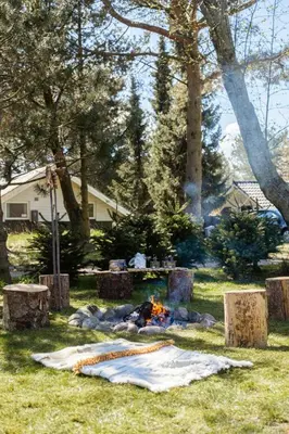 a person sitting around a camp fire in the grass at Authentic Log House Amid Evergreens In Vendsyssel in Fjerritslev