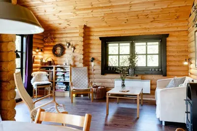 a living room with wooden walls and a table and chairs at Authentic Log House Amid Evergreens In Vendsyssel in Fjerritslev
