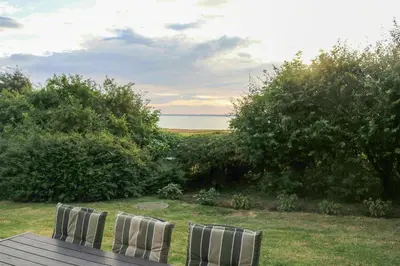 two chairs sitting on a wooden table in a field at Peaceful Summer House Near Limfjorden in Nykøbing Mors