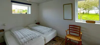 a bedroom with a bed and a chair and a window at Peaceful Summer House Near Limfjorden in Nykøbing Mors