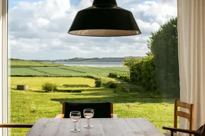 two wine glasses sitting on a wooden table in front of a window at Peaceful Summer House Near Limfjorden in Nykøbing Mors