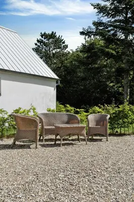 three wicker benches sitting next to a building at Renovated Estate With Private Beach in Roslev