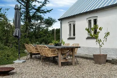 a table with chairs and an umbrella in front of a house at Renovated Estate With Private Beach in Roslev