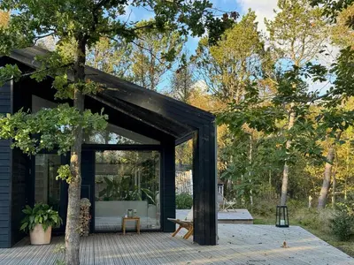 a black house with a tree at Summer House At Thyholm With Fjord View in Thyholm