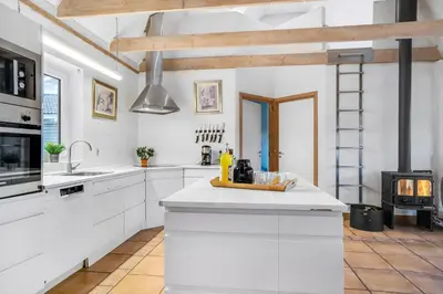 a kitchen with white cabinets and a stove at Large Holiday Home With Pool And Spa In The Middle Of Blokhus Town, Close To The North Sea in Blokhus