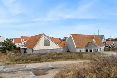 a row of houses behind a wooden fence at Large Holiday Home With Pool And Spa In The Middle Of Blokhus Town, Close To The North Sea in Blokhus