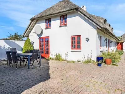 a house with a thatched roof with a table and chairs at Charming Retreat in Blokhus - By Traum Ferienwohnungen in Blokhus