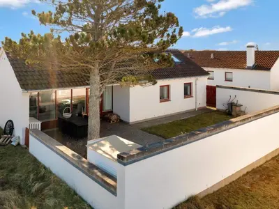 a house with a white wall and a tree at Charming Retreat in Rodhus - By Traum Ferienwohnungen in Pandrup