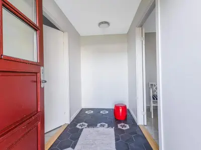 a hallway with a red door and a red stool at Cozy Family Retreat - By Traum Ferienwohnungen in Blokhus