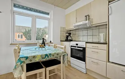 a kitchen with a table and a stove and a window at 2 Bedroom Nice Home In Roslev in Roslev