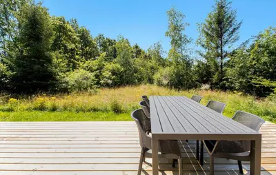 a wooden table with chairs on a wooden deck at 2 Bedroom Pet Friendly Home In Vemb in Vemb