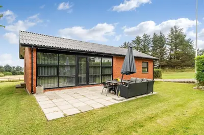 a house with a patio and an umbrella at Lovely Holiday Home, Renovated In 2024, Located In Hanstholm By The North Sea in Hanstholm