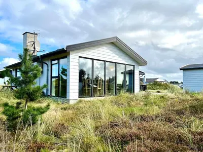a small house with large glass windows on a hill at Hyggeligt feriehus in Thisted