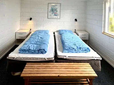 two beds in a room with two tables and two pillows at Hyggeligt feriehus in Thisted