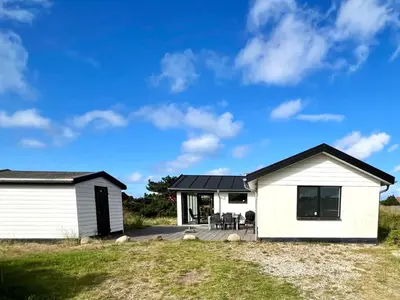a white house with a black roof at Hyggeligt feriehus in Thisted