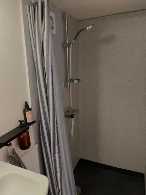 a bathroom with a shower curtain and a sink at Gæstehuset Husly in Haderup