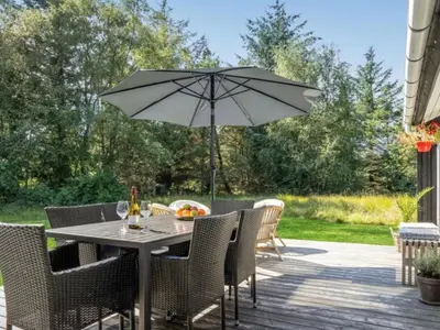 a table and chairs with an umbrella on a patio at Holiday Home Quiana - 2km from the sea by Interhome in Pandrup