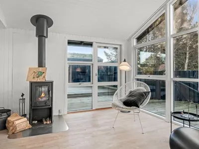 a living room with a fireplace and a chair at Holiday Home Baldo - 800m from the sea by Interhome in Blokhus