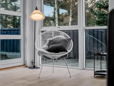 a white chair with a pillow on it in a room with windows at Holiday Home Baldo - 800m from the sea by Interhome in Blokhus