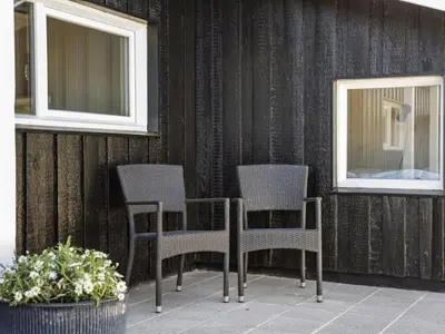 two chairs and a table on a patio with two windows at Holiday Home Erma - 125m from the sea by Interhome in Saltum