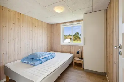 a small bedroom with a bed with a window at Modern Holiday Home From 2017, Located At Lild Strand in Frøstrup