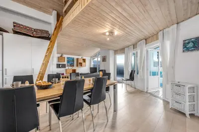 a dining room with a wooden table and chairs at Lovely Holiday Home With Pool, Spa And Sauna, Only 200 Meters From The North Sea in Harboør