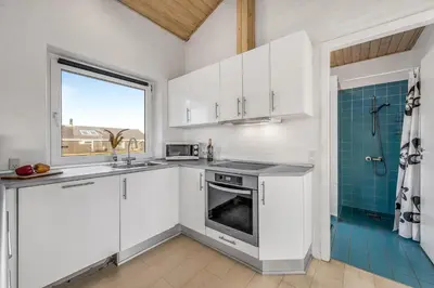 a kitchen with white cabinets and a sink and a window at Lovely Holiday Home With Pool, Spa And Sauna, Only 200 Meters From The North Sea in Harboør