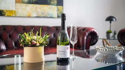 a bottle of wine and a vase of flowers on a table at Hotel Palads Apartments in Viborg