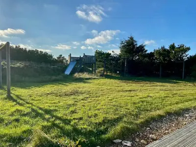 a field of grass with a staircase in the distance at Vesterhavsluft Og Natur Ved Nationalpark Thy in Thisted