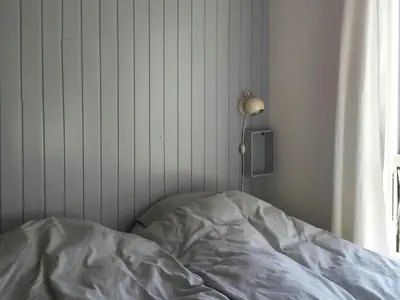 an unmade bed in a bedroom next to a window at Summer House In The Dunes Near The West Sea in Saltum