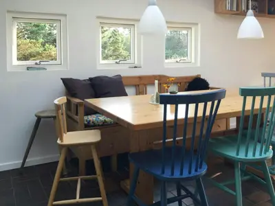 a kitchen with a wooden table and blue chairs at Summer House In The Dunes Near The West Sea in Saltum
