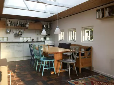 a kitchen with a wooden table and blue chairs at Summer House In The Dunes Near The West Sea in Saltum