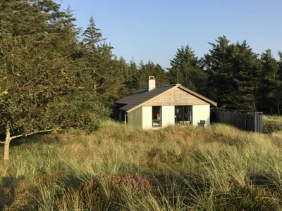 an old house in the middle of a field at Summer House In The Dunes Near The West Sea in Saltum