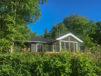 a house with a large deck in the woods at Stunning Sunrises Over Harre Vig in Roslev