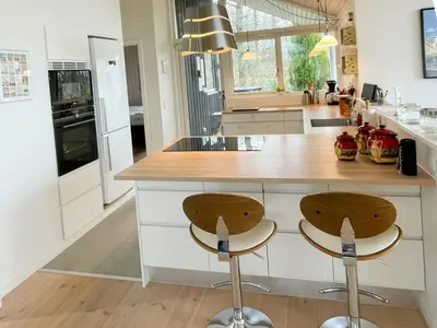 a kitchen with a counter and two stools in it at Stunning Sunrises Over Harre Vig in Roslev