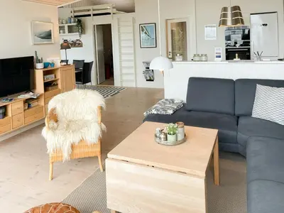 a living room with a blue couch and a table at Stunning Sunrises Over Harre Vig in Roslev