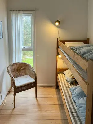 a bedroom with a bunk bed and a chair and a window at Nature-Rich Oasis With Views Over The Limfjord in Roslev